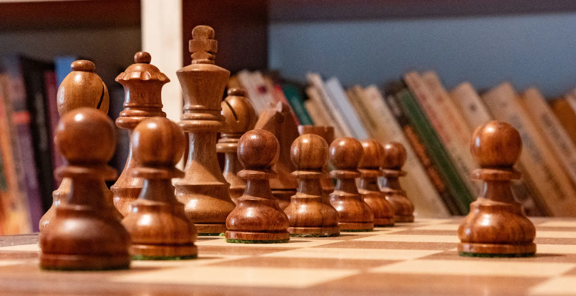 Wooden chess pieces with library background